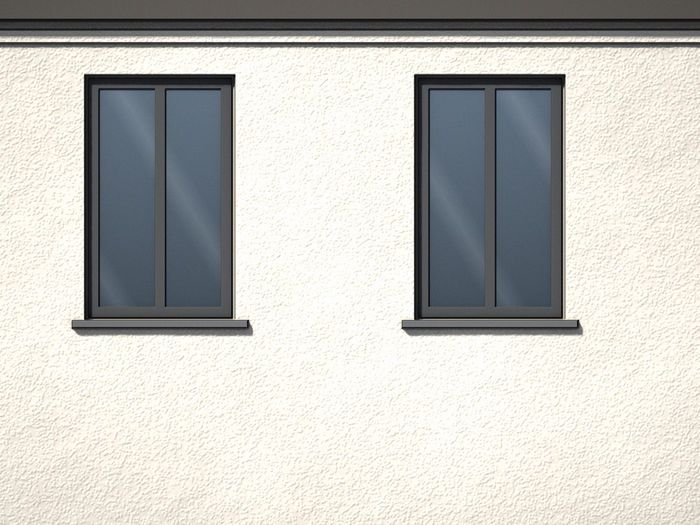 Verputzte Fassade mit zwei Fenstern und Blechbänken